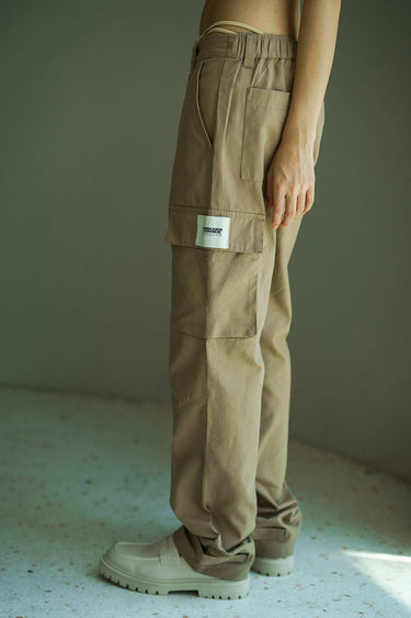 Beige cargo pants with utility pockets from Bonkers Corner, showcasing relaxed fit and functional design.