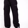 Black cargo pants by Bonkers Corner featuring multiple pockets and a relaxed fit, shown in a casual outdoor setting.