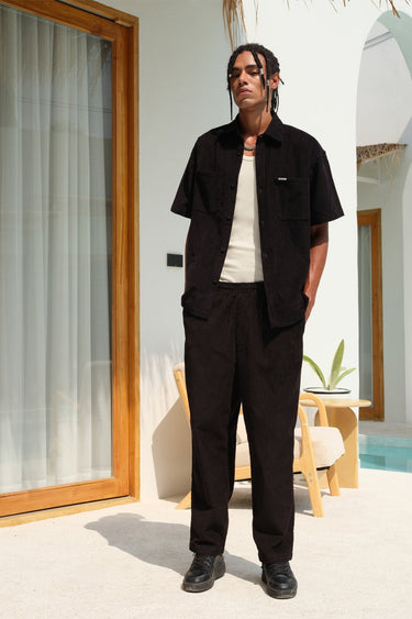 Black corduroy pants by Bonkers Corner, featuring a slim fit and textured fabric, shown on a model.
