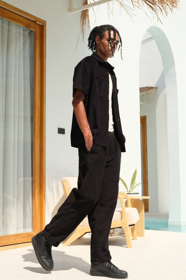 Black corduroy pants by Bonkers Corner, slim fit with textured fabric, shown laid flat with waistband and pockets visible.