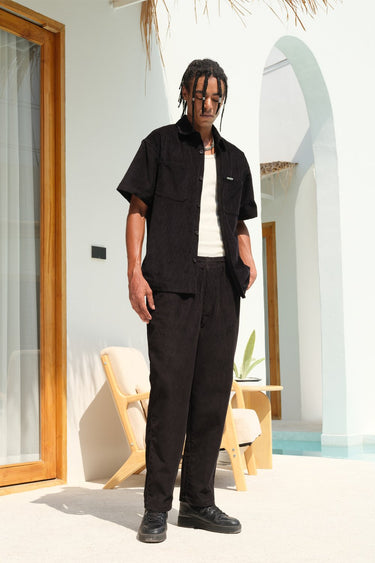 Black corduroy pants by Bonkers Corner, slim fit style with textured fabric and classic design, shown on a model.
