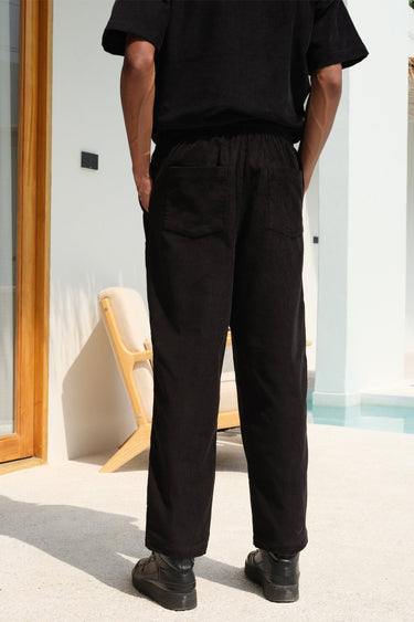 Black corduroy pants by Bonkers Corner, shown on a model, featuring a slim fit and classic texture.