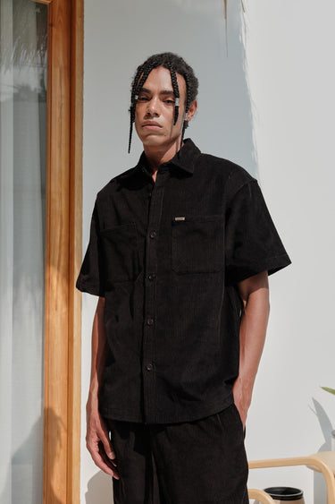 Black corduroy shirt by Bonkers Corner, shown in a close-up image highlighting the textured fabric and classic button-down design.