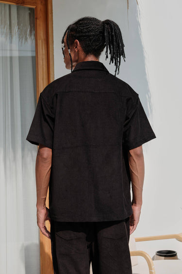 Black corduroy shirt by Bonkers Corner, shown on a model, featuring a classic collar and button-up front.
