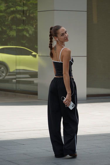 Black essential cami top by Bonkers Corner, close-up of fitted sleeveless design with thin straps on a white background.