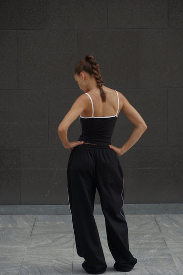 Black Essential Cami Top by Bonkers Corner, close-up of the sleek, fitted camisole with thin straps on a neutral background.