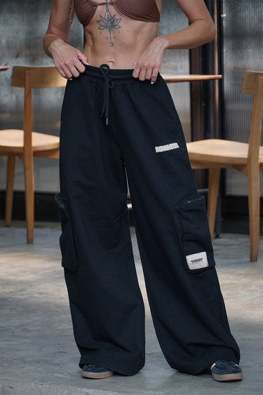 Black heavyweight cargo pants with multiple pockets, made by Bonkers Corner, shown on a model. Durable and stylish casual wear.