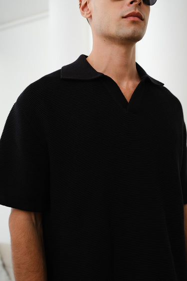 Black knit textured polo T-shirt from Bonkers Corner, featuring a classic collar and short sleeves on a plain background.