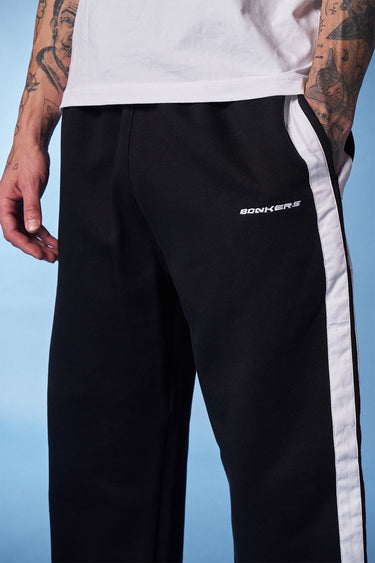 Black sporty straight-fit pants by Bonkers Corner, shown laid flat with elastic waistband and tapered leg design.
