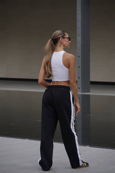 Black sporty straight fit pants by Bonkers Corner, shown on a model with a casual streetwear style.