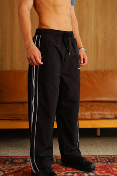 Black wide leg joggers with tape details from Bonkers Corner, featuring a relaxed fit and comfortable fabric.