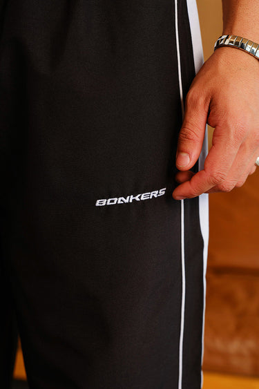 Black tape wide leg joggers from Bonkers Corner, featuring a relaxed fit and comfortable fabric.