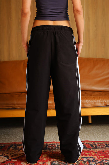 Black Tape Wide Leg Joggers by Bonkers Corner featuring a relaxed fit and elastic waistband, shown on a model.