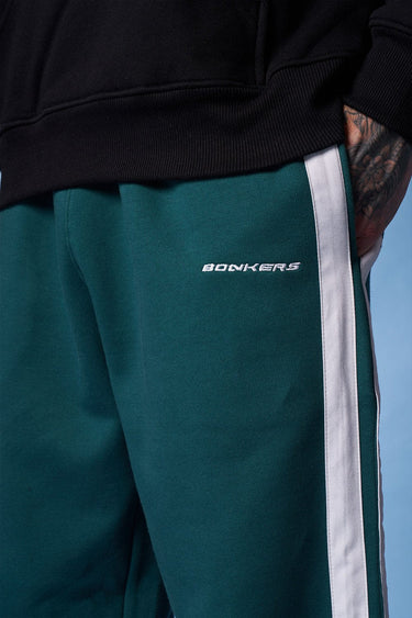 Bottle green sporty straight fit pants by Bonkers Corner, shown laid flat with elastic waistband and tapered legs.