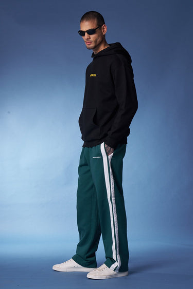 Bonkers Corner bottle green sporty straight fit pants, shown on a model, featuring comfortable design and athletic style.