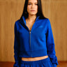 Electric blue crop zipper jacket by Bonkers Corner, shown on a hanger with front zipper and long sleeves.