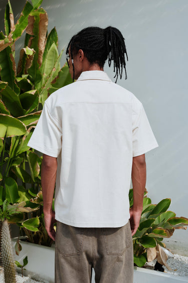 Bonkers Corner Off White Corduroy Shirt displayed on a hanger, showcasing its textured fabric and classic collar design.
