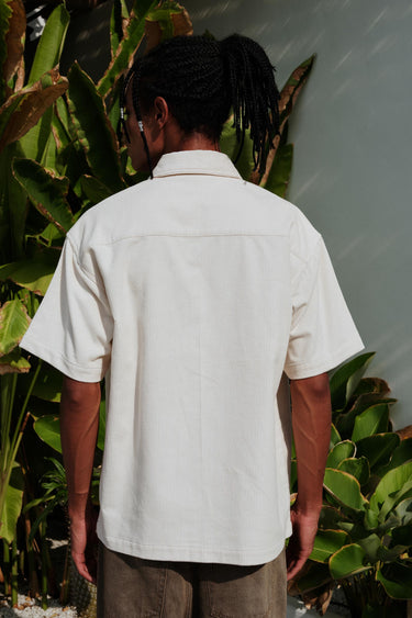 Off White corduroy shirt by Bonkers Corner, featuring a classic collar and textured fabric, shown on a hanger.